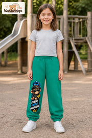 Mädchen trägt grüne Jogginghose mit Frech wild Affe-Print, von vorn auf dem Spielplatz.