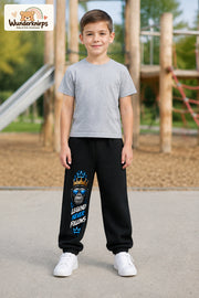 Junge trägt schwarze Jogginghose mit Legend Never Follows-Print, von vorn auf dem Spielplatz.
