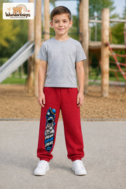 Junge trägt rote Jogginghose mit Dream Explore Create-Print, von vorn auf dem Spielplatz.