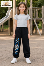 Mädchen trägt schwarze Jogginghose mit Dream Explore Create-Print, von vorn auf dem Spielplatz.