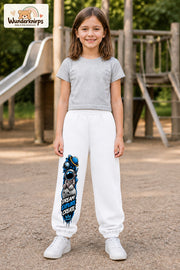 Mädchen trägt weiße Jogginghose mit Dream Explore Create-Print, von vorn auf dem Spielplatz.