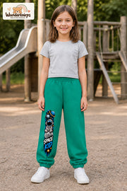 Mädchen trägt grüne Jogginghose mit Space Kid Mondreise-Print, von vorn auf dem Spielplatz.