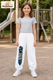 Mädchen trägt weiße Jogginghose mit Space Kid Mondreise-Print, von vorn auf dem Spielplatz.