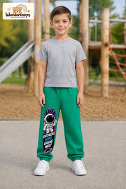 Junge trägt grüne Jogginghose mit Eigene Welt Astronaut-Print, von vorn auf dem Spielplatz.
