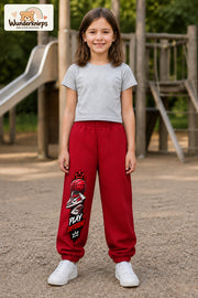 Mädchen trägt rote Jogginghose mit Play Different Basketball-Print, von vorn auf dem Spielplatz.