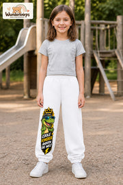 Mädchen trägt weiße Jogginghose mit Coole Kinder Sonnenbrillen-Dino-Print, von vorn auf dem Spielplatz.