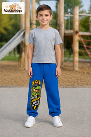 Junge trägt blaue Jogginghose mit Coole Kinder Daumen-Dino-Print, von vorn auf dem Spielplatz.