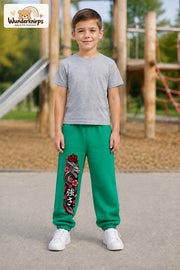 Junge trägt grüne Jogginghose mit Roter Blütendrache-Print, von vorn auf dem Spielplatz.