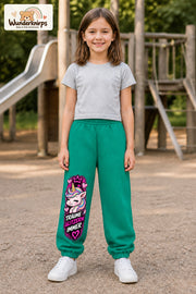 Mädchen trägt grüne Jogginghose mit Träume glitzern Einhorn-Print, von vorn auf dem Spielplatz.