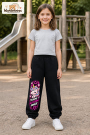 Mädchen trägt schwarze Jogginghose mit Träume glitzern Einhorn-Print, von vorn auf dem Spielplatz.