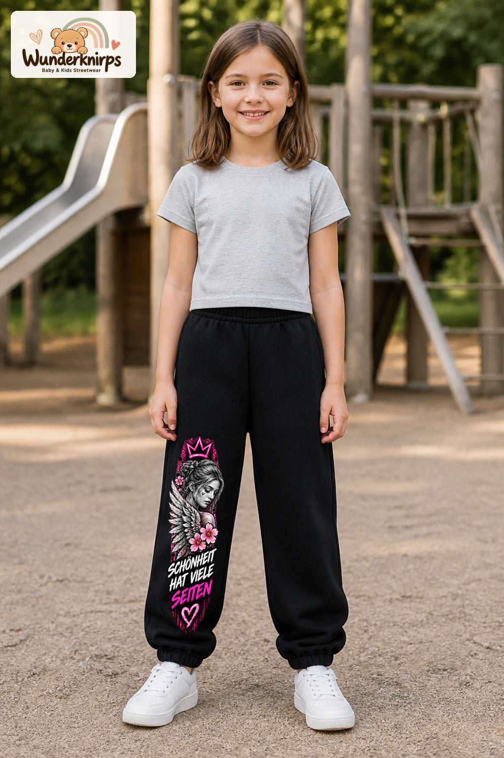 Mädchen trägt schwarze Jogginghose mit Schönheit mit vielen Seiten-Print, von vorn auf dem Spielplatz.