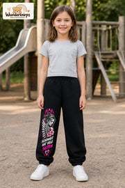 Mädchen trägt schwarze Jogginghose mit Schönheit mit vielen Seiten-Print, von vorn auf dem Spielplatz.