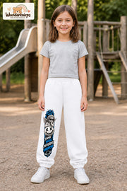 Mädchen trägt weiße Jogginghose mit Same Soul Engel-Print, von vorn auf dem Spielplatz.
