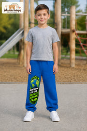 Junge trägt blaue Jogginghose mit Bessere Zukunft Erde-Print, von vorn auf dem Spielplatz.