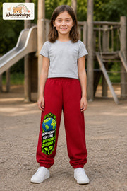 Mädchen trägt rote Jogginghose mit Bessere Zukunft Erde-Print, von vorn auf dem Spielplatz.