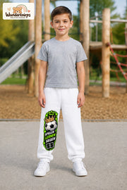 Junge trägt weiße Jogginghose mit Siegen Fußballstern-Print, von vorn auf dem Spielplatz.