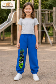 Mädchen trägt blaue Jogginghose mit Game Zone Controller-Print, von vorn auf dem Spielplatz.