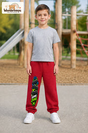 Junge trägt rote Jogginghose mit Game Zone Controller-Print, von vorn auf dem Spielplatz.