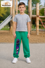Junge trägt grüne Jogginghose mit Level Up Gaming-Print, von vorn auf dem Spielplatz.