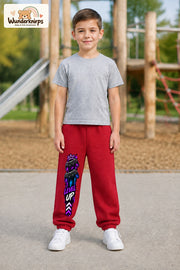 Junge trägt rote Jogginghose mit Level Up Gaming-Print, von vorn auf dem Spielplatz.