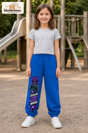 Mädchen trägt blaue Jogginghose mit Zocken Lernen Controller-Print, von vorn auf dem Spielplatz.