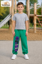 Junge trägt grüne Jogginghose mit Zocken Lernen Controller-Print, von vorn auf dem Spielplatz.