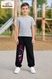 Junge trägt schwarze Jogginghose mit Next Level Controller-Print, von vorn auf dem Spielplatz.