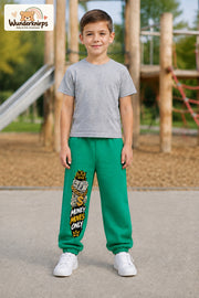 Junge trägt grüne Jogginghose mit Money Moves Gold-Print, von vorn auf dem Spielplatz.