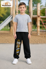 Junge trägt schwarze Jogginghose mit Money Moves Gold-Print, von vorn auf dem Spielplatz.