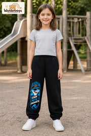 Mädchen trägt schwarze Jogginghose mit Stark einzigartig Cap-Hai-Print, von vorn auf dem Spielplatz.
