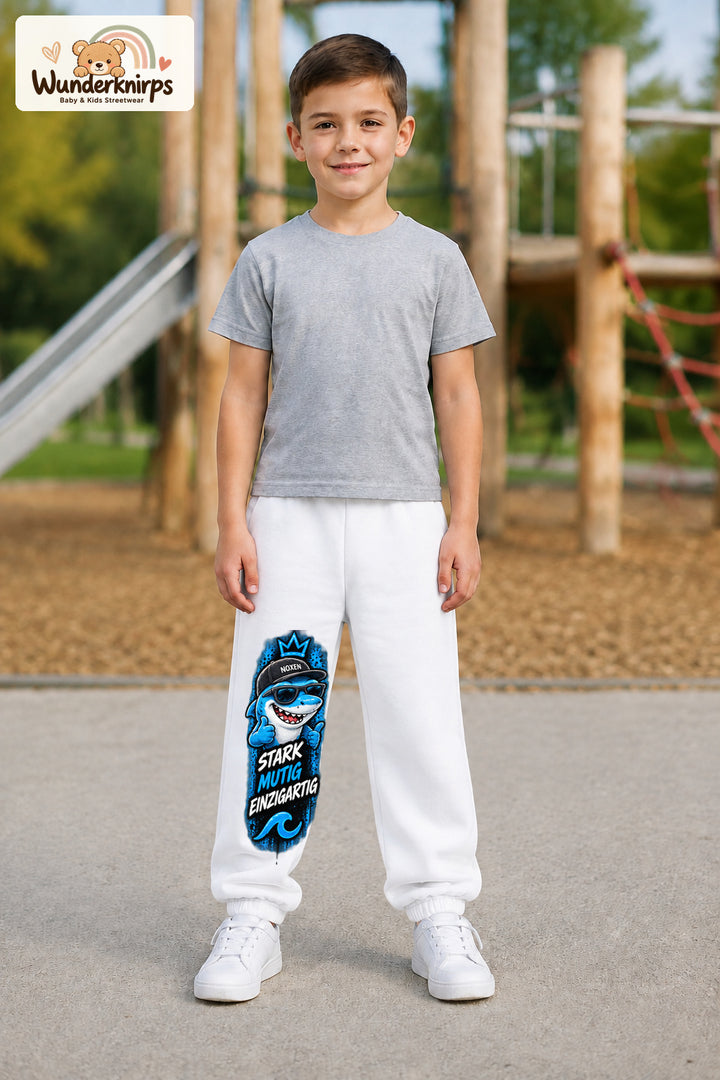 Junge trägt weiße Jogginghose mit Stark einzigartig Cap-Hai-Print, von vorn auf dem Spielplatz.
