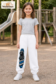 Mädchen trägt weiße Jogginghose mit Discipline Hoodie-Print, von vorn auf dem Spielplatz.