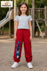 Mädchen trägt rote Jogginghose mit No Limits Hoodie-Print, von vorn auf dem Spielplatz.