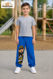 Junge trägt blaue Jogginghose mit Gute Laune Cap-Hund-Print, von vorn auf dem Spielplatz.