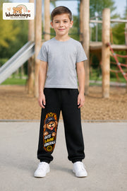 Junge trägt schwarze Jogginghose mit Gute Laune Hoodie-Hund-Print, von vorn auf dem Spielplatz.