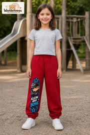 Mädchen trägt rote Jogginghose mit Klein aber Boss Cap-Print, von vorn auf dem Spielplatz.