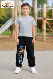 Junge trägt schwarze Jogginghose mit Kleine Schritte Skater-Print, von vorn auf dem Spielplatz.