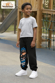 Junge trägt schwarze Jogginghose mit Kleine Schritte Skater-Print, leicht seitlich auf dem Spielplatz.