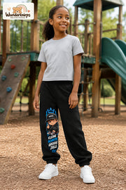 Mädchen trägt schwarze Jogginghose mit Kleine Schritte Skater-Print, leicht seitlich auf dem Spielplatz.