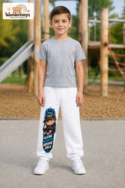 Junge trägt weiße Jogginghose mit Kleine Schritte Skater-Print, von vorn auf dem Spielplatz.
