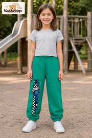 Mädchen trägt grüne Jogginghose mit Street Life Karo-Print, von vorn auf dem Spielplatz.