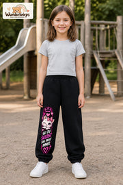 Mädchen trägt schwarze Jogginghose mit Sei du selbst Kätzchen-Print, von vorn auf dem Spielplatz.