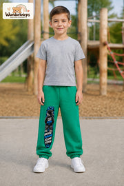 Junge trägt grüne Jogginghose mit Große Träume Mini-Boss-Print, von vorn auf dem Spielplatz.