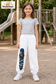 Mädchen trägt weiße Jogginghose mit Eigener Weg Kompass-Print, von vorn auf dem Spielplatz.