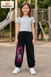 Mädchen trägt schwarze Jogginghose mit Musik macht besser-Print, von vorn auf dem Spielplatz.