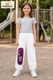 Mädchen trägt weiße Jogginghose mit Musik macht besser-Print, von vorn auf dem Spielplatz.