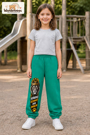 Mädchen trägt grüne Jogginghose mit Stärke von innen Löwe-Print, von vorn auf dem Spielplatz.