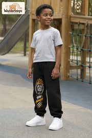 Junge trägt schwarze Jogginghose mit Stay Hungry Löwe-Print, leicht seitlich auf dem Spielplatz.