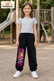 Mädchen trägt schwarze Jogginghose mit Große Träume Herz-Bandana-Print, von vorn auf dem Spielplatz.