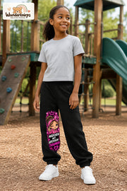 Mädchen trägt schwarze Jogginghose mit Große Träume Herz-Bandana-Print, leicht seitlich auf dem Spielplatz.